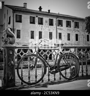 Fahrrad mit dem Kanal in Treviso, Venetien, Italien. Schwarz-Weiß-Stadtfotografie Stockfoto