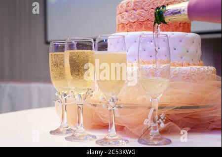 Nahaufnahme von Gläsern Champagner mit einem dreilagigen customized Kuchen im Hintergrund Stockfoto