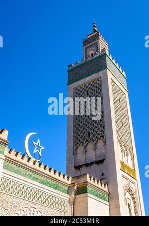 Blick in den Winkel des 33 Meter hohen Minaretts der Großen Moschee von Paris, Frankreich, mit dem Stern und der Sichel über dem Eingang gegen blauen Himmel. Stockfoto