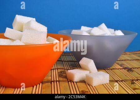 Zwei bunte Schüssel voll mit weißen Zuckerwürfeln. Stockfoto