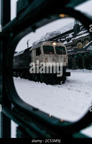 Schmutziger Güterzug, der im Winter den Bahnhof verlässt. Stockfoto