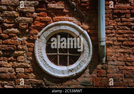 Venedig Italien. Altes, kreisförmiges Vintage-Fenster in einer alten Ziegelwand. Stockfoto