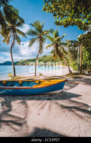 Mahe Island, Seychellen. Lokale lebendige farbige Boot unter Kokospalmen an sonnigen Tag am Ufer des tropischen Strandes. Stockfoto