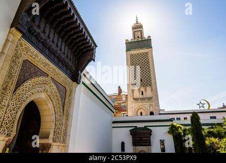 Blick aus dem Winkel auf das Minarett der Großen Moschee von Paris, im Hintergrund vom Garten mit einer Tür und dem Stern und der Sichel. Stockfoto