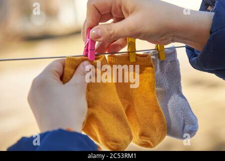 Mama hängt kleine Baby Socken auf einer Wäscheleine zum Trocknen Stockfoto