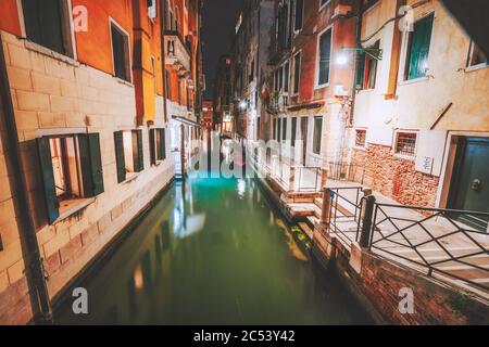 Venezia schmale Kanal und Gondelboote in Lagunenstadt Venedig bei Nacht. Italien. Lebhafte farbige alte Backsteingebäude Straße. Stockfoto