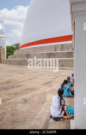 Frauen sitzen vor dem weißen Dagoba, Kuppeldach eines Tempels in Sri Lanka Stockfoto