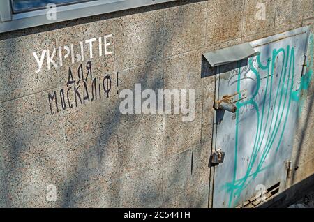 Dnipro, Ukraine - 08. April 2020: Alter Eingang zum Bombenschutzhaus im Keller des Wohngebäudes, beschädigt durch Vandalen. Inschrift lautet - Schutz, re Stockfoto