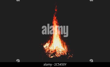 Helle riesige Flamme in der Dunkelheit der Natur. Sommerfeuer auf dem Campingplatz in einer dunklen Nacht. Stockfoto