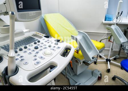 Gynäkologischer Schrank mit Stuhl und medizinischer Ausrüstung für die Ultraschalldiagnostik im Klinikraum Stockfoto