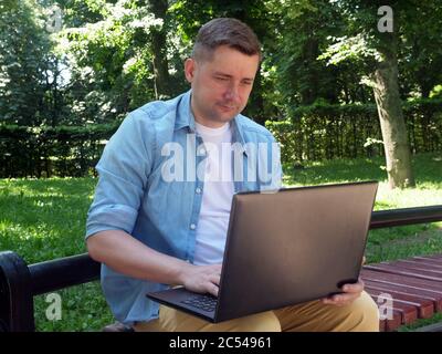 Kommunikationskonzept. Junger Mann im Park im Internet chatten. Stockfoto