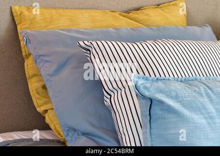 Nahaufnahme von gelben und hellblauen Kissen in einer Reihe auf dem Bett, moderne Retro-Dekoration für zu Hause, Pastell hellen Farben bunt hell Stockfoto