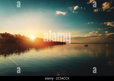 Sonnenuntergang im Wolga-Delta. Eine Flusslandschaft mit einem Fischerboot. Astrachan Region, Russland. Hochwertige Fotos Stockfoto