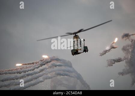 Militärische Kampfhubschrauber feuern Fackeln in der Dämmerung, thermischer Schutz für Raketenangriff. Stockfoto