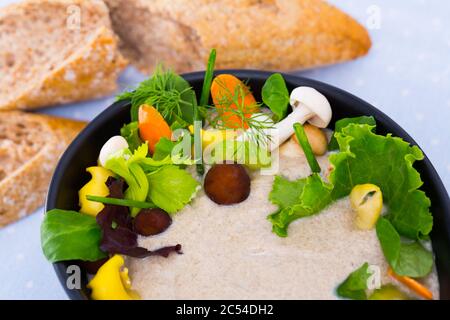 Leckere Cremesuppe mit verschiedenen Pilzen garniert mit geschnittene Karotten, Sellerie und Grüns, serviert mit Brot Stockfoto