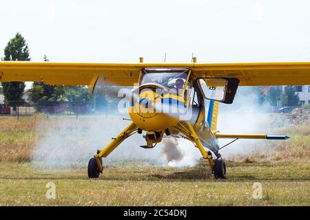 Leichtes Flugzeug der allgemeinen Luftfahrt mit Rauch, der während des Motorstarts aus der Auspuffanlage austicht. Kleine gelbe Ebene mit Stol (kurzer Start und Landung) Stockfoto