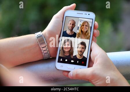 Videokonferenz mit einer Gruppe von Menschen. Junge Frau, die mit vielen Menschen auf ihrem Handy einen Video-Chat hat. Stockfoto