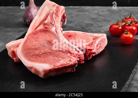 Zwei Stücke Schweinefleisch auf einem Schieferteller auf einem grauen Hintergrund. Kopierraum, Foto für Lebensmittelgeschäfte Stockfoto