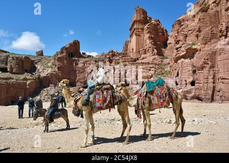 PETRA, JORDANIEN - APR 2, 2015: Nabatäer Hauptstadt. Nicht identifizierter Einheimischer auf einem Kamel wartenden Touristen. Petra's Tempel, Gräber, Theater und andere BU Stockfoto