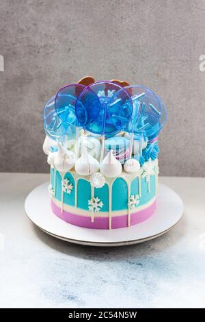 Blauer Winterkuchen mit weißer Schokolade, Lutscher und fondanten Schneeflocken. Grauer Hintergrund. Stockfoto