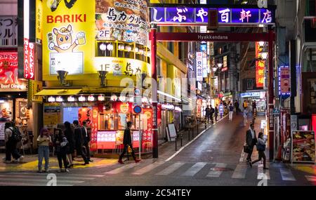 Menschen, die nachts auf dem Bürgersteig in Shibuya, Tokio, Japan, spazieren gehen. Stockfoto