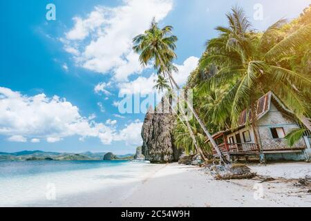 Urlaub auf Palawan - El Nido Island Hopping Tour. Einsame, menschenleere Hütte unter Palmen, Felsen im Hintergrund. Stockfoto