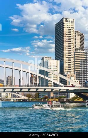 tokio, japan - märz 15 2020: Wasserbusse fahren auf dem Sumida-Fluss unter der Bogenbrücke von Tsukiji Ohashi, die von der Kanni-Straße mit dem Skyscra überquert wird Stockfoto