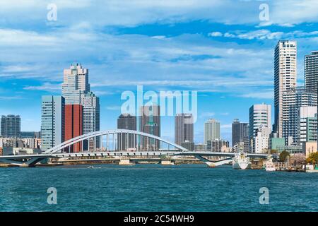 tokio, japan - märz 15 2020: Bogenbrücke von Tsukiji Ohashi am Sumida-Fluss mit den festgetäuten Booten der Bucht von Tokio und den Wolkenkratzern der Tsukiji Stockfoto