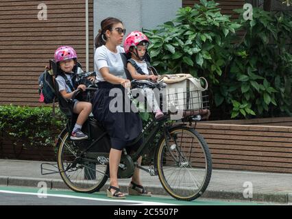 Japanische Mütter, die in der Tokyo Street, Japan, mit dem Fahrrad von Mamachari fahren. Stockfoto