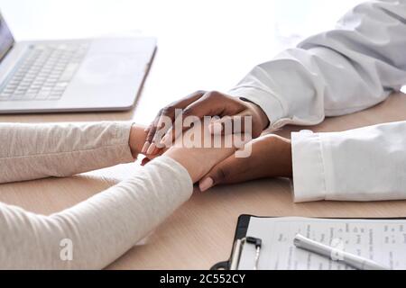 Afrikanische Ärztin mit der Hand, die kaukasische Patientin unterstützt, Nahaufnahme. Stockfoto