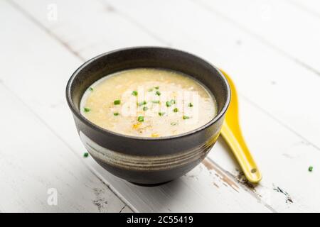 Maissuppe auf weißem Hintergrund. Ein kantonesisches Gericht, das in chinesischen Restaurants oft als Vorspeise serviert wird. Die Schüssel mit Suppe ist auf weißem Hintergrund. Stockfoto