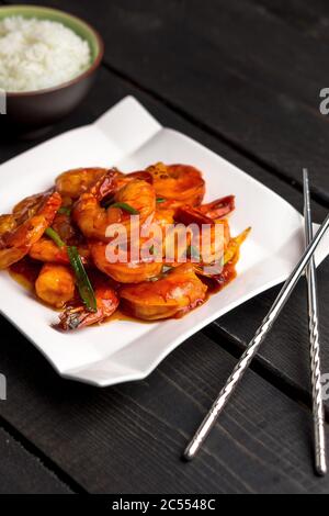 Ketchup Garnelen vertikale Hochformat Ansicht. Ketchup Garnelenteller mit Schüssel mit Reis und Essstäbchen gewinkelte Ansicht. Ein klassisches chinesisches Gericht, das große Shrim verwendet Stockfoto