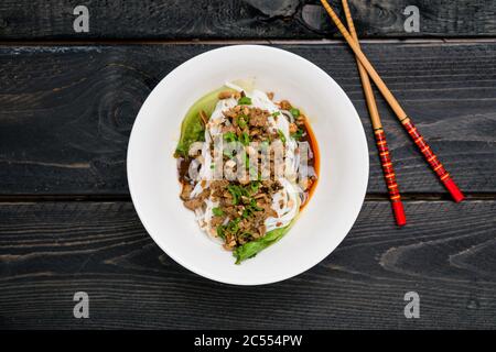 Dan Dan Noodles Draufsicht. Dan Dan Noodles ist ein würziges Szechuan-Gericht, das häufig in chinesischen Straßenessen zu finden ist. Zutaten sind dicke Reisnudeln Stockfoto