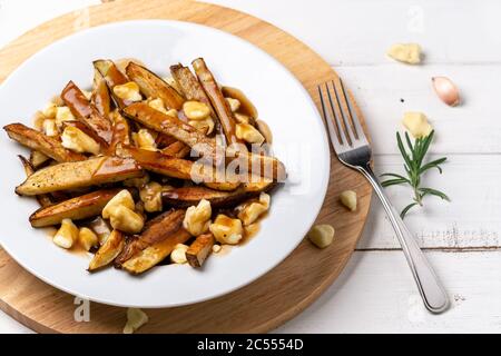 Poutine Komfort Nahrung Nahaufnahme. Ein klassisches Fast-Food-Gericht aus Quebec. Dieses kanadische Komfortessen wird mit pommes Frites gemischt mit leckeren Käs zubereitet Stockfoto