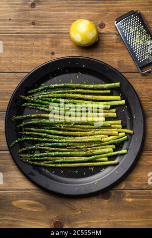 Gekochter Spargel von oben. Gesunde Ernährung ist mit diesem hausgemachten veganen Gericht einfach; gebratener Spargel mit Zitronenschale darauf. Das Gemüse ist serviert Stockfoto