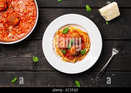 Spaghetti und Fleischbällchen Teller Draufsicht. Italienische Pasta-Gericht in weißen Teller auf schwarzem Holzhintergrund serviert. Spaghetti und Fleischbällchen sind wie Bolognese Stockfoto