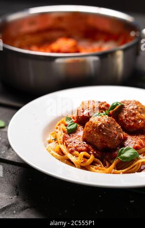 Spaghetti Fleischball Porträt Seitenansicht. Italienische Pasta-Gericht in weißen Teller auf schwarzem Holzhintergrund serviert. Spaghetti und Fleischbällchen sind wie Bolognese Stockfoto
