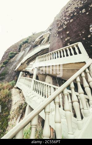 Vertikale Aufnahme der weißen antiken Treppe, die an der Klippe Stockfoto