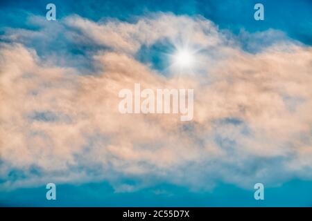 Ein heller leuchtender Stern strahlt durch die flauschigen weißen Wolken Stockfoto