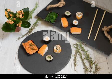 Nahaufnahme von Sushi-Rollen mit Essstäbchen auf schwarzen Tellern Stockfoto