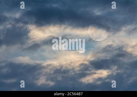 Ein Vollmond steigt zwischen den Wolken in einem Tag Zeit Himmel Stockfoto