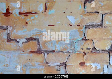 Alte Vintage-Puder-blaue abblätternde Farbe an einer Ziegelwand mit Rissen im Verfall Stockfoto
