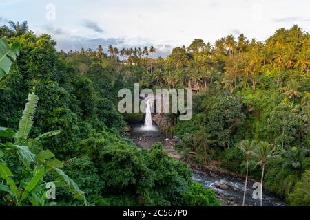 Tegenungan Wasserfall bei Sonnenuntergang. Tropische Palmen und üppiger Dschungel umgeben dieses weltberühmte Wahrzeichen und ein muss für Touristen auf Bali. Stockfoto
