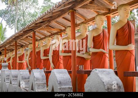 Viele Statuen buddhistischer Mönche stehen in einer langen Linie an einer Wand, Sri Lanka Stockfoto