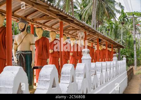 Viele Statuen buddhistischer Mönche stehen in einer langen Linie an einer Wand, Sri Lanka Stockfoto