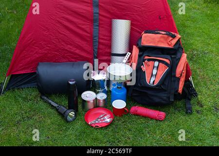 Foto von Campinggeräten auf dem Rasen - Rucksack, Zelt, Tank, Dosen, Kompass, etc - bereit, in den Wald zu gehen Stockfoto