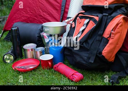 Foto von Campinggeräten auf dem Rasen - Rucksack, Zelt, Tank, Dosen, Kompass, etc - bereit, in den Wald zu gehen Stockfoto