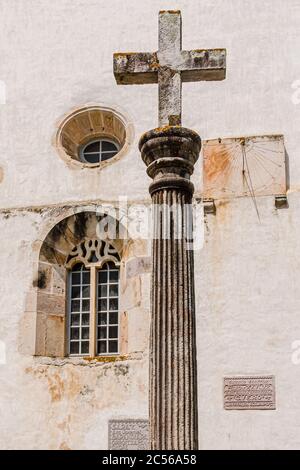 Steinkreuz und Sonnenuhr an der Kirchenwand in Espelette Stockfoto