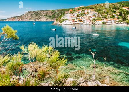 Assos Dorf, Insel Kefalonia, Griechenland. Farbenfrohe Häuser und transparente türkisfarbene Bucht, umgeben von grünen Kiefern. Stockfoto