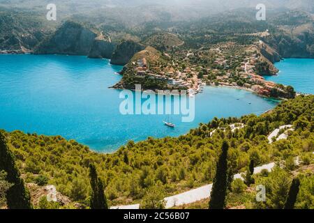 Draufsicht auf das Dorf Assos. Landmark Place der Insel Kefalonia. Einsame weiße Jacht vor Anker in ruhiger, schöner Lagune, umgeben von Pinien und Zypress TR Stockfoto